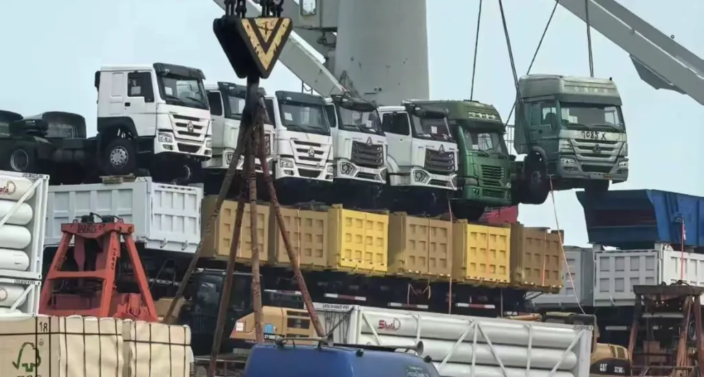 Used trucks waiting for export from China to Senegal — HOWO and Shacman dump trucks at the port yard