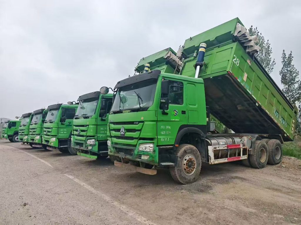 HOWO dump trucks at a Chinese export yard ready for inspection. These are properly aged used trucks over 180 days old, so the 180-day export rule does not apply. African buyers can import these without manufacturer letters.