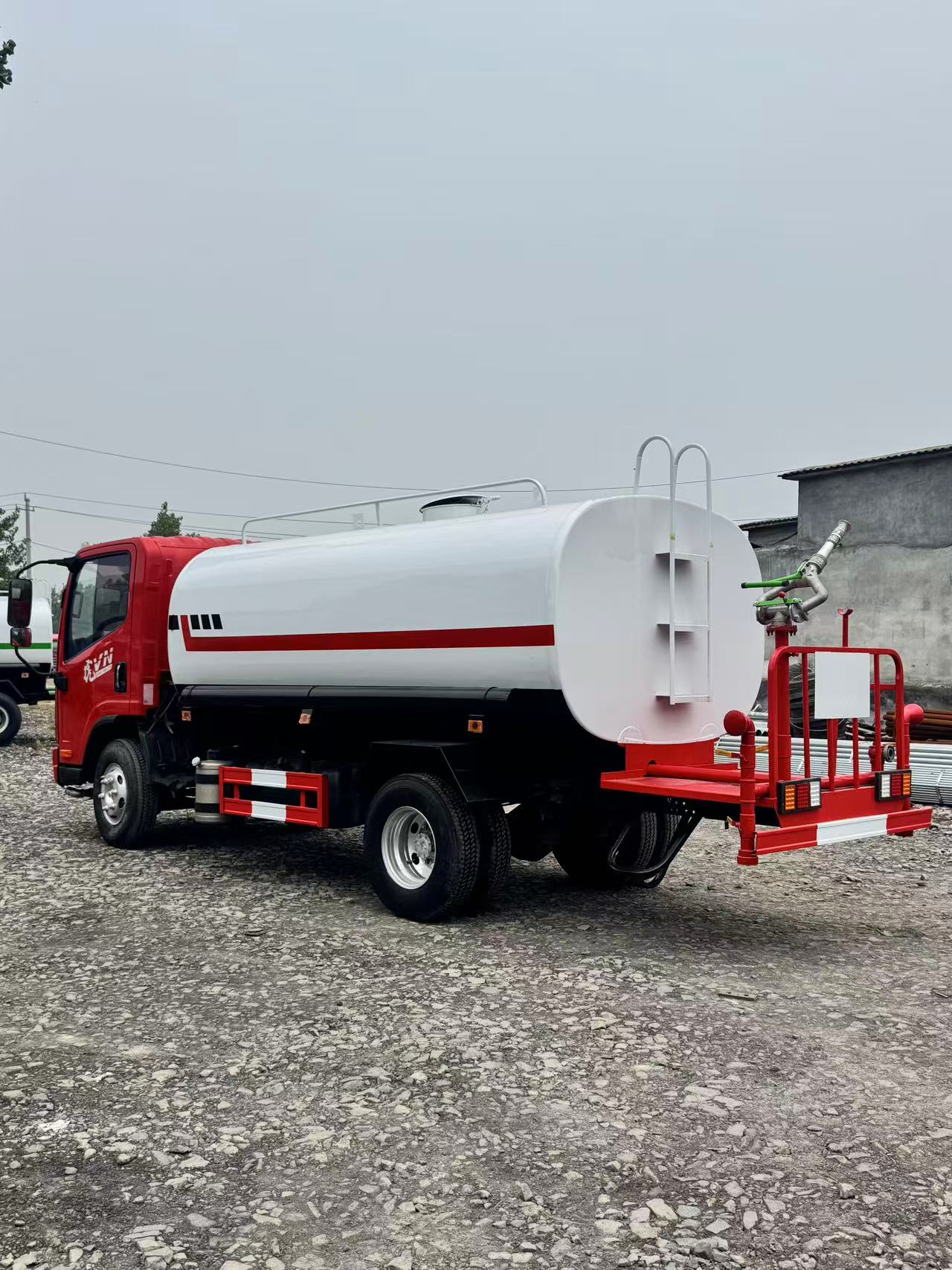 Side view of a water truck at a Chinese depot or port, showing tank, chassis and spray system clearly.